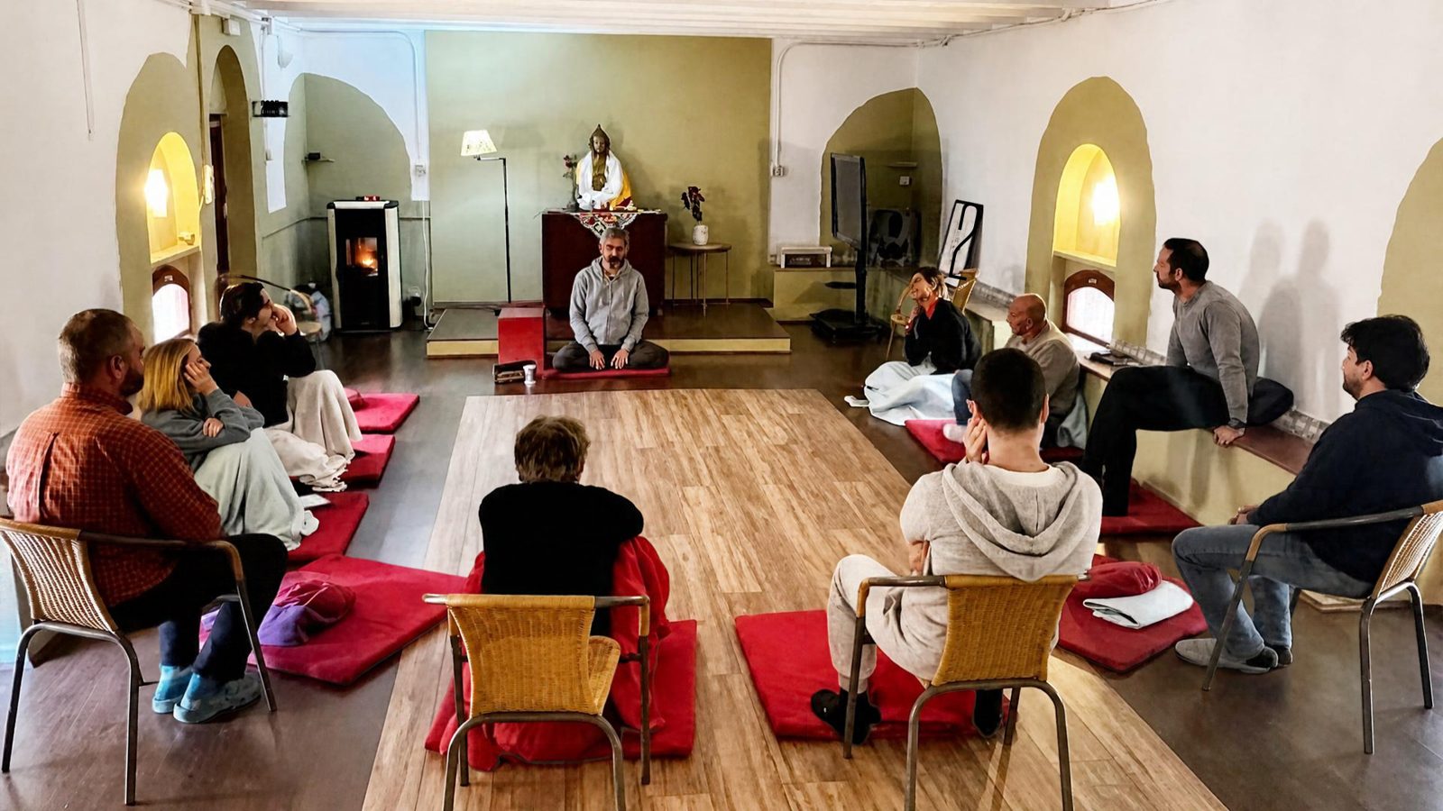 A small group seated in a circle in a quiet vaulted room during a guided reflection session